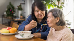 Caregiving helping elder eat soup