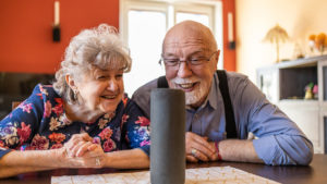Senior woman and man smiling at Alexa device
