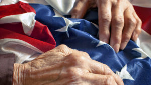 Veterans affairs benefits - two elderly hands touching the American flag